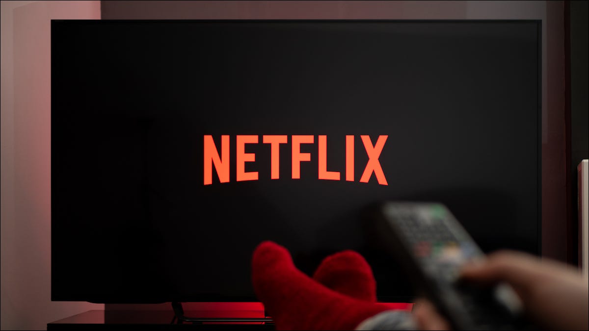 netflix logo on a smart tv and a person holding a remote